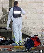 An Israeli forensic expert covers a body at the scene of the explosion