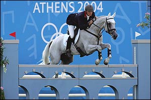 Leslie Law of leads his horse Shear L'Eau over an obstacle 