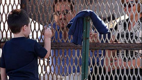 Un niño juega con adultos a través de la cerca. Foto: María Teresa Fernández
