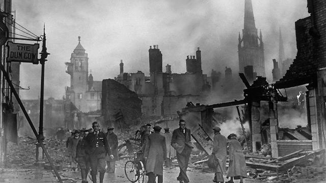 People in Coventry walk to work past smouldering piles of rubble after a bombing raid in 1940.
