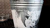 A metal bucket with ice on the outside