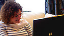 Kaliya smiling as she uses her laptop