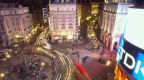 The neon lights shine over a stream of pedestrians flowing through this West End junction