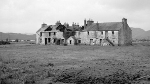 Black and white view of a two-storey block of workers' houses at Bonawe Furnace. the centre of the block is abandoned with no roof and missing windows.