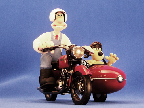 Wallace and Gromit on a bike, being filmed in front of a blue screen