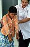 Photo Susan Schulman: Physiotherapist Som Piseth supports a young client as she gets used to walking with her new orthopaedic brace