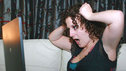 Kaliya clutches the sides of her head in frustration as she uses Facebook on her laptop