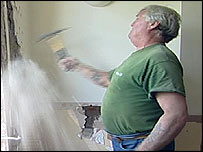 A workman hammers at a wall