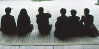Japanese people sitting in front of a Zen rock garden, with one man explaining something to the others