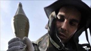 A Libyan rebel arms his rocket-propelled grenade (RPG) launcher at a check point outside the city of Brega on March 27, 2011