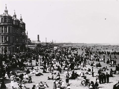 A large beach crowded with various people in Victorian dress.