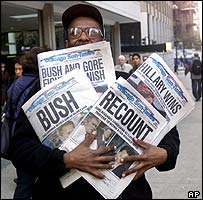 2000'de seçim sonuçlarını bildiren gazeteleri taşıyan bir Amerikalı