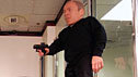 Warwick in a scene from 'ShortFellas', dressed for a bank robbery with a stocking on his head, and holding a handgun